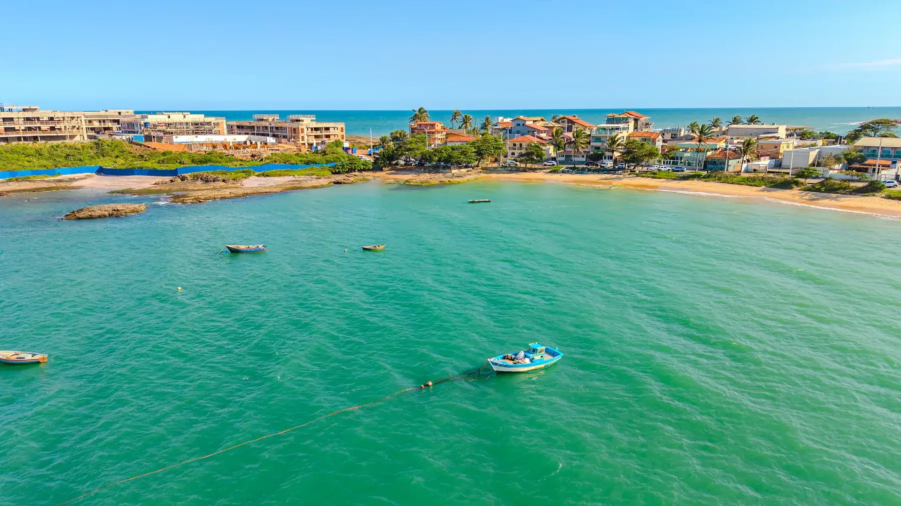 A enseada de Guaibura vista de drone, com barcos de pesca ancorados na água verde e a orla baixa ao fundo